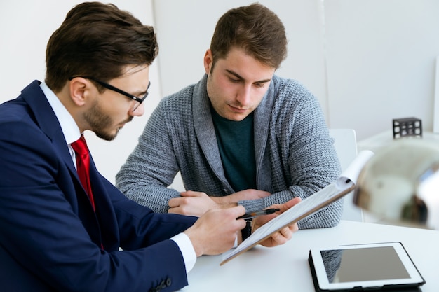 A tax professional advising a client, reviewing documents and using a tablet to display financial data and tax strategies.