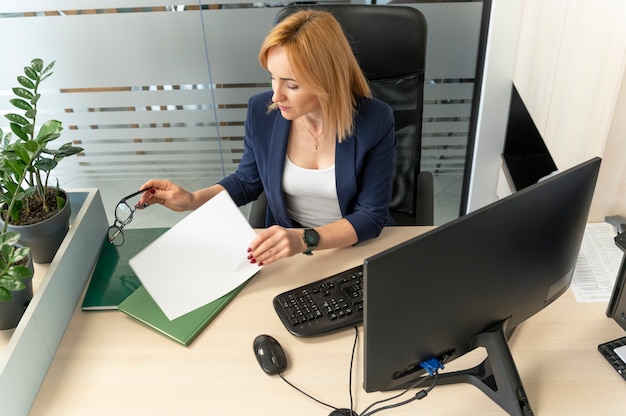 A person sitting at a desk, focused on filling out an application form with supporting documents such as ID, resume, and certificates neatly organized nearby. The scene conveys diligence and preparation.