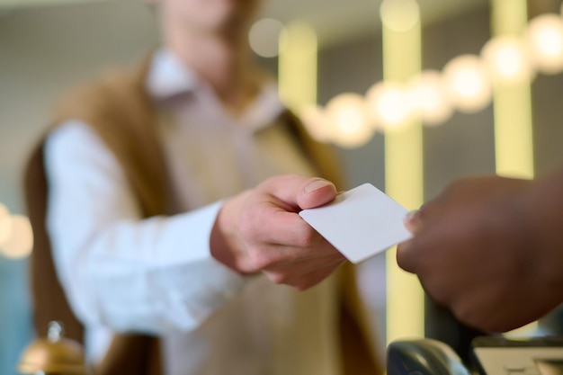 A person confidently handing out a business card to another individual at a technology conference, surrounded by various exhibitors and attendees. The focus should be on the exchange of the card and the professional setting.