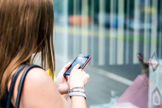 A close-up of a smartphone screen displaying a secret shopping app, showing available assignments and their pay rates. The background is blurred, suggesting a busy urban environment.