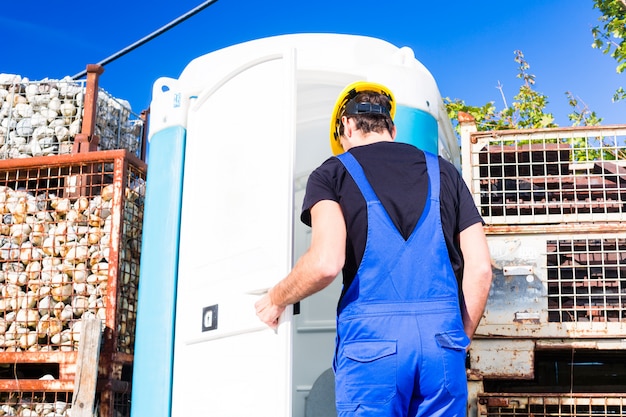 A craftsman is holding a high-efficiency heat pump, focusing on the efficiency labels, with tools and a home exterior in the background.
