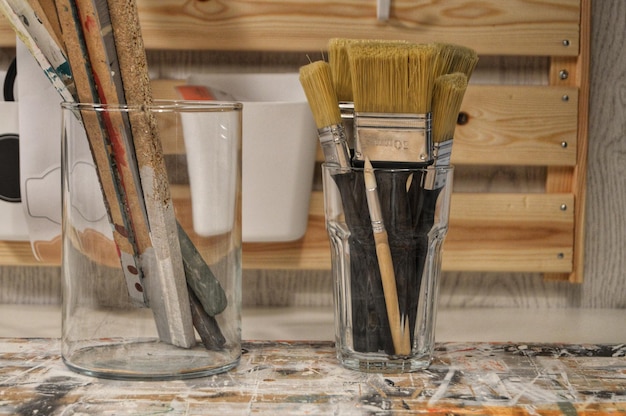 An organized workbench with various home improvement supplies, including paint cans, brushes, sandpaper, and safety glasses. Sunlight streams in from a nearby window.