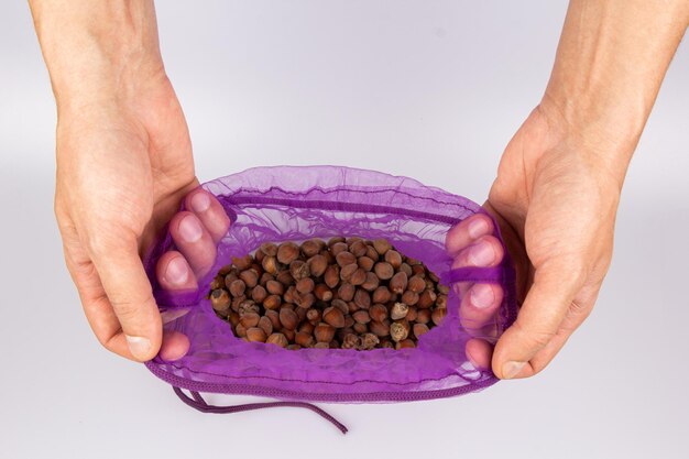A close-up shot of a hand holding a small sample bag of cat food, with a curious cat sniffing at it. The background should be blurred to keep the focus on the hand and the sample.