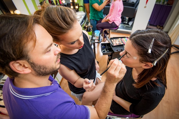 A brightly lit interior of a Sephora store during a makeup tutorial event, with several participants gathered around a makeup artist demonstrating product application.