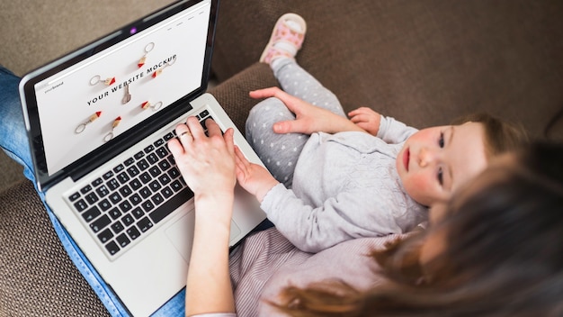 A person browsing a website on their laptop, surrounded by various baby products, illustrating the search for online freebies.