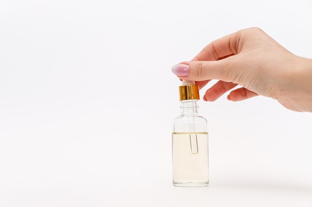 A close-up of a hand carefully opening a small, elegantly designed perfume sample vial on a clean, white surface.
