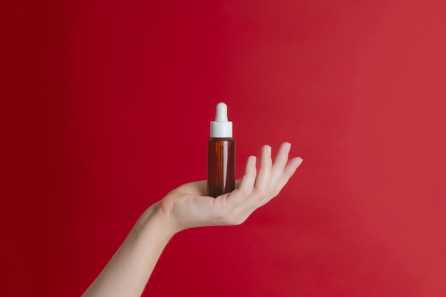 A hand carefully holding a small tube of serum, with a blurred background showing a well-lit bathroom counter. The focus is on the texture and consistency of the serum as it is about to be applied to the skin.
