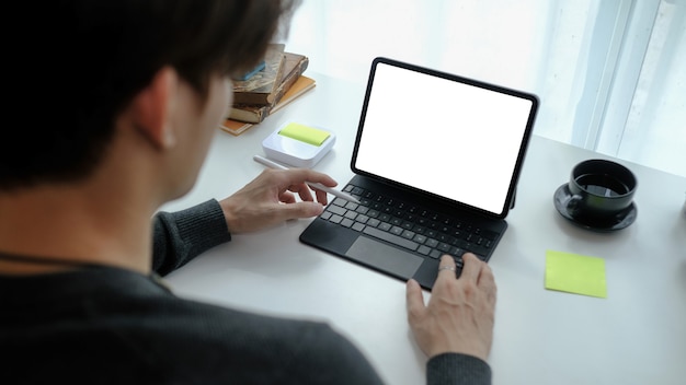 A person sitting at a table, looking at a laptop screen. The screen shows a coffee brand's website with a prominent 