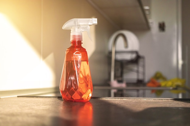 A close-up shot of various miniature cleaning product bottles lined up on a kitchen counter, with labels clearly visible and a blurred background of a modern kitchen.