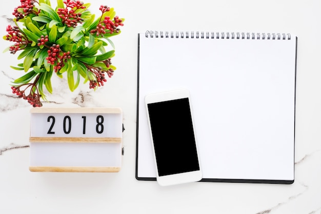A close-up of a free 2025 wall calendar hanging on an office wall. The calendar page shows the month of January with important dates marked. A pen is hanging from the calendar's spiral binding.