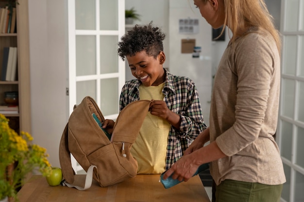 A volunteer handing a backpack filled with school supplies to a smiling child at a back-to-school event organized by a local charity. Other volunteers and children are visible in the background, creating a sense of community and support.
