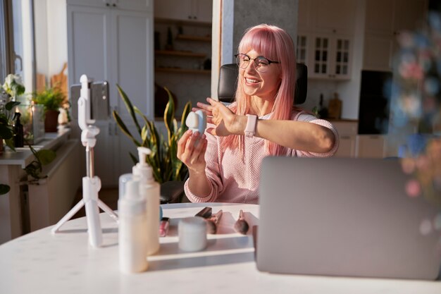 A person sitting at a desk, excitedly filling out an online form on a laptop, with several small sample products (shampoo, lotion) visible in the background. Expression shows delight and anticipation.