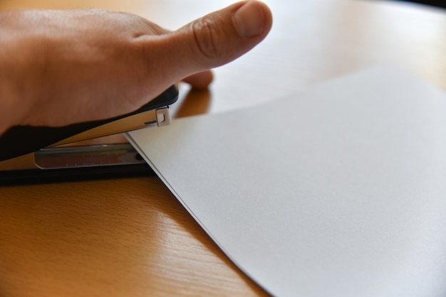 A close-up shot of hands holding a TANF application form, with a pen resting on top. The background is blurred but suggests a government building or social services office. Focus on the detail and texture of the form and hands to convey the paperwork involved in applying for TANF.