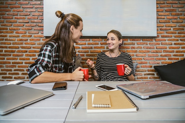 A friendly case worker sitting at a desk, smiling and talking with a mother holding a child. The scene is in an office setting, with files and paperwork visible in the background, conveying support and collaboration.