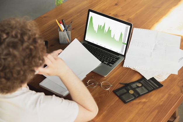 A person using a laptop with a graph showing a downward trend in student loan debt. The scene is set in a modern, brightly lit workspace.