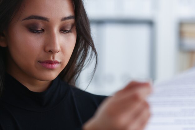 A close-up shot of a female entrepreneur filling out a government grant application form. She is focused and determined, with a pen in her hand and relevant documents spread across her desk.