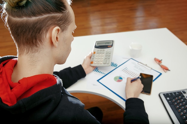 A person using a calculator and reviewing financial documents, symbolizing the assessment of income and resources for MSP eligibility.