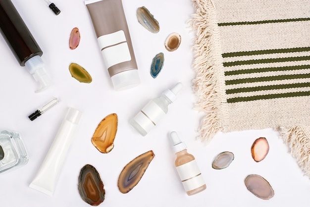 A close-up shot of various beauty product samples arranged on a clean, white surface. The samples include small bottles of skincare lotions, tiny tubes of makeup, and miniature perfume vials. There are also small brushes and applicators included. The lighting is bright and even, emphasizing the textures and colors of the products.