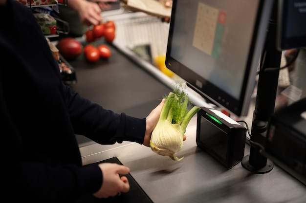 A close-up of an EBT card being swiped at a grocery store checkout, with the cashier and various food items visible in the background.