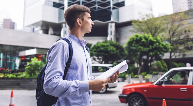 An employee filling out a mileage log in their car, parked in front of an office building. The focus is on the logbook and pen, with the office building slightly blurred in the background.