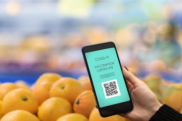 A hand using the Walmart app on a smartphone to scan the barcode of a product on a shelf in a Walmart store. The app displays the product's price and any available rollback savings. The background shows other products on the shelf, slightly blurred.