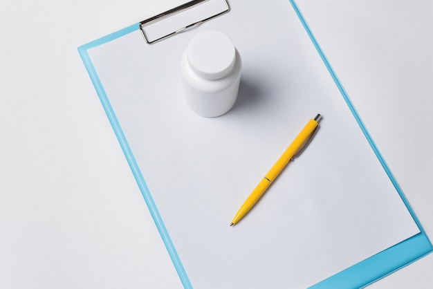 A close-up shot of an application form for Medicaid, with a pen hovering over the signature line. The form is set against a backdrop of medical bills and prescription bottles, illustrating the financial burden of healthcare.
