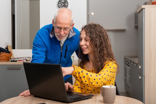 A split screen showing two scenarios. On the left, a single mother working diligently at a computer. On the right, an elderly man sitting with a caregiver in a comfortable living room, both smiling.