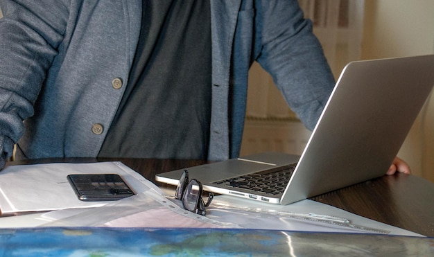An office setting with a person working on a laptop, surrounded by papers and financial documents. The scene depicts the typical work environment of a freelance professional.